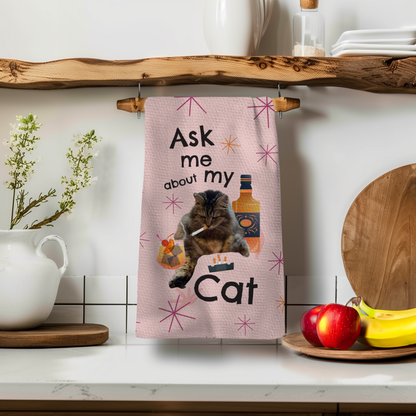 Ask About My Cat towel featuring a cat graphic, pink background, and decorative elements on a kitchen shelf.