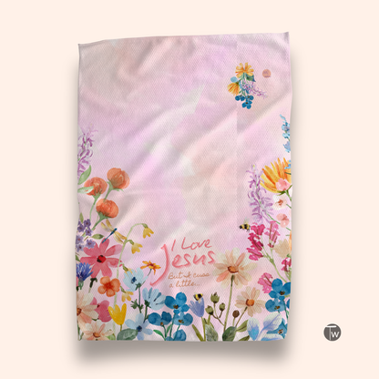 I Love Jesus but I cuss a little towel featuring colorful floral designs on a pastel background.