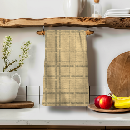 F-ity plaid illusion towel in beige hanging on a wooden shelf with apples and bananas nearby.