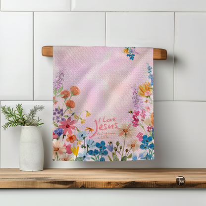 I Love Jesus but I Cuss a Little towel with floral design, hanging on a wooden rack against a tiled wall.