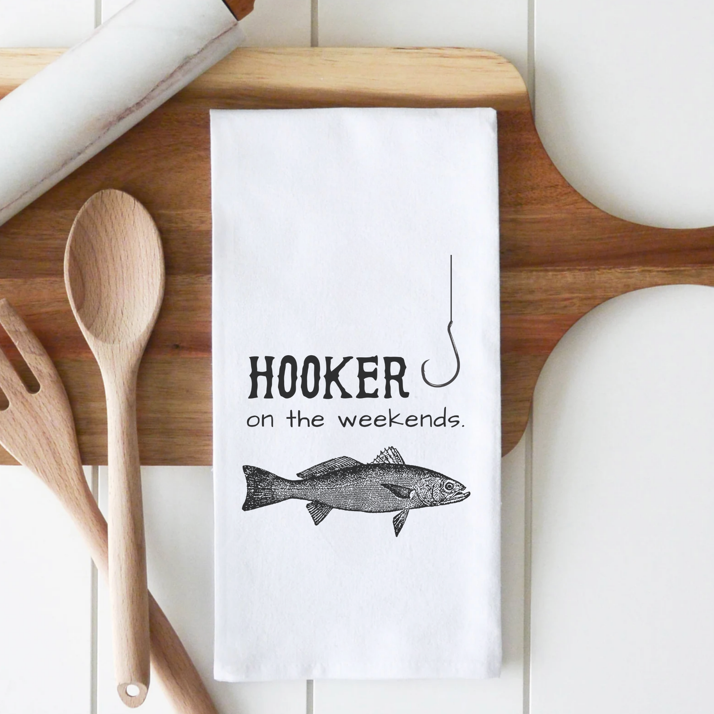 White cotton tea towel featuring the text "Hooker on the weekends" and an illustration of a fish and fishing hook.