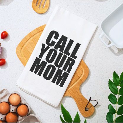 Call Your Mom funny cotton tea towel displayed on a wooden cutting board with tomatoes and eggs around it.
