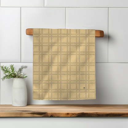 F-ity plaid illusion towel in soft yellow, hanging on a wooden rack with a white vase and greenery nearby.