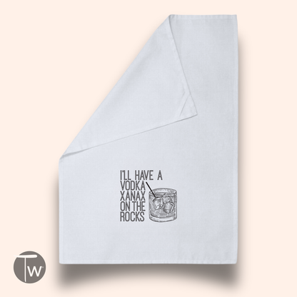 White cotton tea towel featuring the text "I'll have a vodka Xanax on the rocks" and an illustration of a drink with ice.