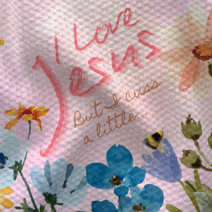 I Love Jesus but I cuss a little towel with floral design in pastel colors and handwritten text.