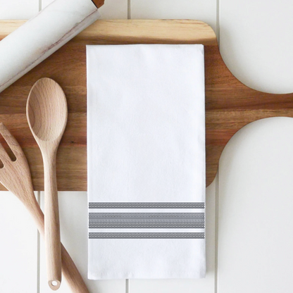 Fckity Stripe Illusion black cotton tea towel with black striped pattern on a wood cutting board