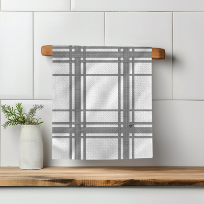 Fkity Fk Illusion Perfect Towel in white with gray plaid pattern, hanging on a wooden rod against a tiled wall.