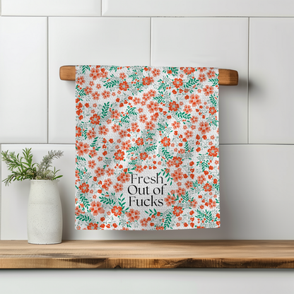 Floral towel with red and green patterns, featuring the text "Fresh Out of Fucks," hanging on a wooden rack.