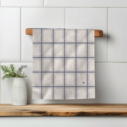 Fresh Out Plaid Illusion kitchen tea towel with a grid pattern in light gray and white, hanging on a wooden rod.