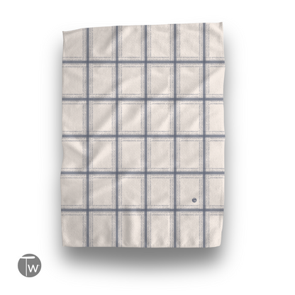 Fresh Out plaid illusion kitchen tea towel in light beige with blue grid pattern, folded and displayed flat.