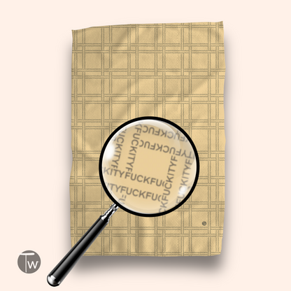 F-ity plaid illusion towel in beige with a textured pattern and magnifying glass highlighting the design.
