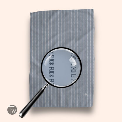 Colette Stripe Illusion towel in light gray with white stripes, featuring a magnifying glass highlighting text.