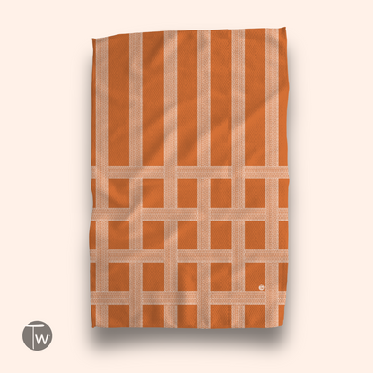Vintage Shitshow towel in orange with a grid pattern and logo in the bottom left corner, displayed flat.
