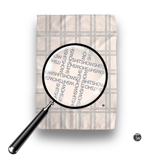 Shitshow plaid towel in retro beige color with a magnifying glass highlighting the text design.
