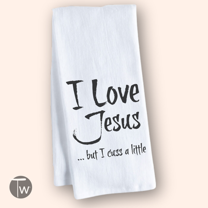 White cotton tea towel featuring the text "I Love Jesus but I cuss a little" in black font.